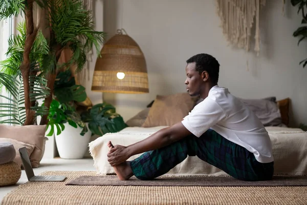 African young man sitting in paschimottanasana or Intense Dorsal Stretch pose, seated forward bend posture Royalty Free Stock Photos