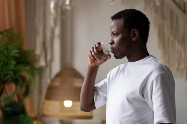 African athlete at home with glass of water after sport training. Stock Photo