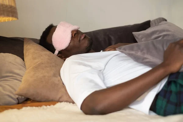 Knappe etnische zwarte Afrikaanse man rustend in bed slapen of slapen. — Stockfoto