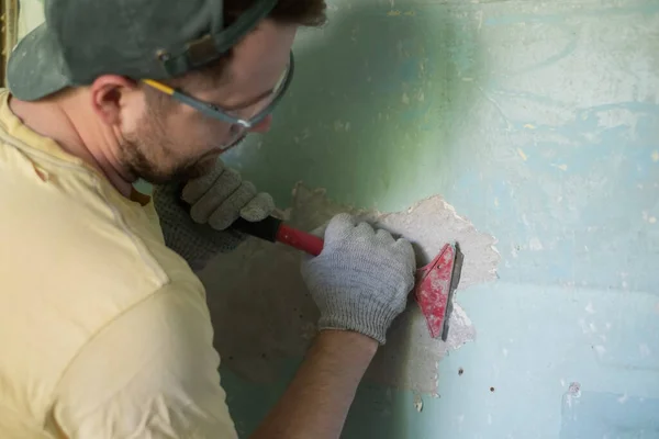 Hombre caucásico quitando pintura vieja con herramienta de raspador. — Foto de Stock