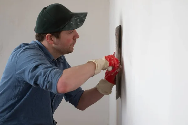 Trabajador artesano con cuchillo de masilla que trabaja en el relleno de la pared del apartamento — Foto de Stock