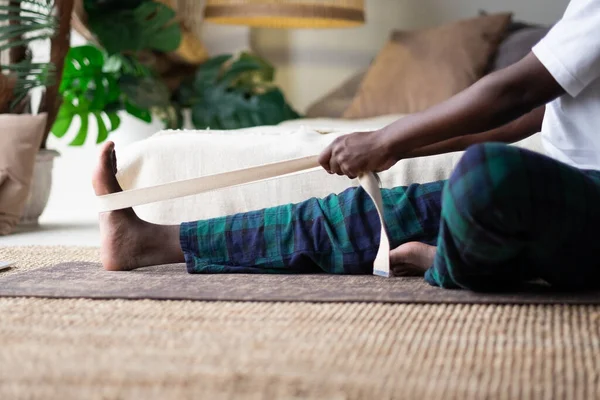 Young african man sitting in janushirshasana seated forward bend posture at home — Stock Photo, Image