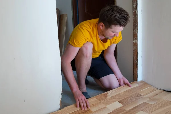 Homem caucasiano instalar placa de parquet de madeira durante o trabalho de piso — Fotografia de Stock