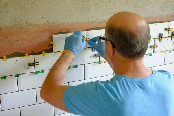 Trabalhador colocando telhas na parede na cozinha. — Fotografia de Stock