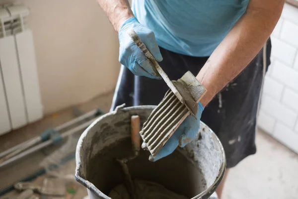 Hombre aplicando adhesivo sobre baldosas durante la renovación plana. — Foto de Stock