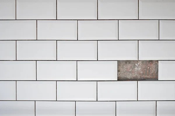 Foro sulla parete di piastrelle bianche in ceramica. Una piastrella mancata sul muro. — Foto Stock