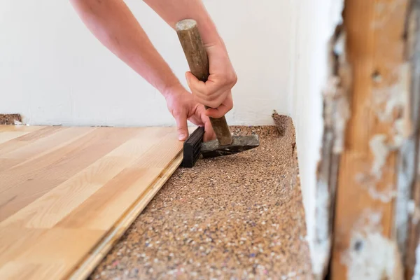 Arbetstagare installera trä parkettbord under golvarbete med hammare — Stockfoto