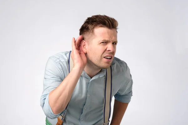 Hombre poniendo la mano cerca de la oreja escuchando un sonido tranquilo o prestando atención — Foto de Stock