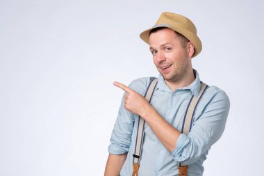 Şapkalı mutlu genç adam işaret parmağıyla kopyasal uzayı işaret ediyor..