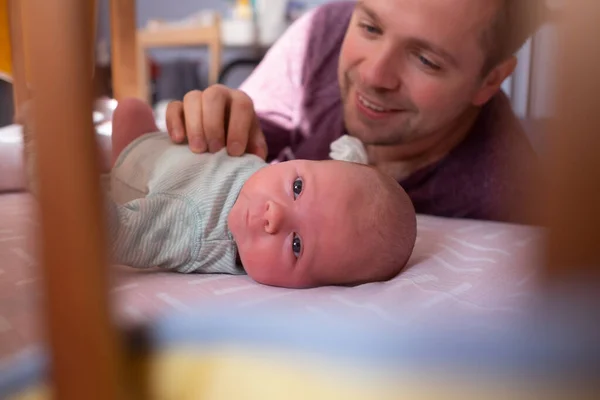 Young father checking his newborn baby girl in bed — Stock Photo, Image