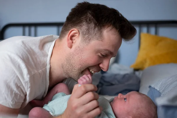 Young father checking his newborn baby girl in bed — Stock Photo, Image