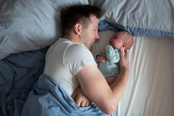 युवा पिता बिस्तर में अपने नवजात बेबी लड़की का समय बिता रहा है — स्टॉक फ़ोटो, इमेज