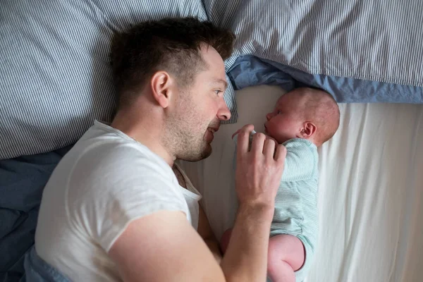 Young father spending time his newborn baby girl in bed — Stock Photo, Image