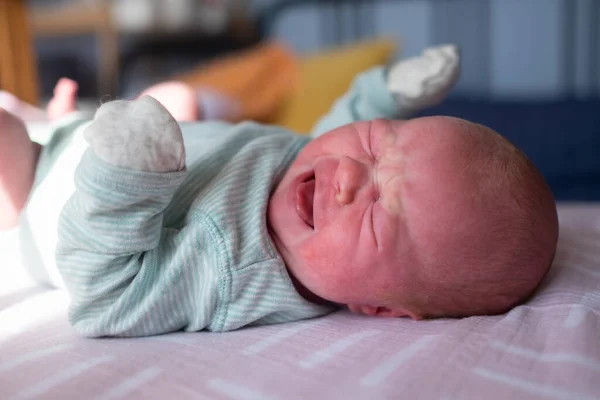Little crying caucasian newborn baby on her bed suffering from colic — Stock Photo, Image