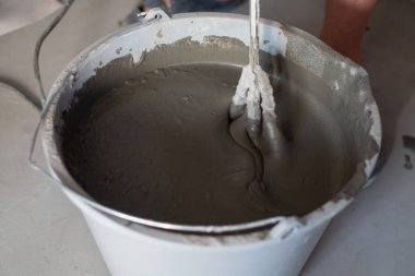 Döşeme tamiri için kovaya beton karıştırılıyor.