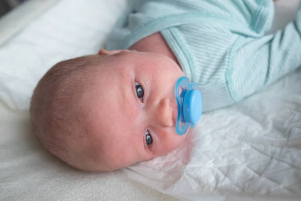 Cute baby girl with a pacifier in her mouth — Stock Photo, Image