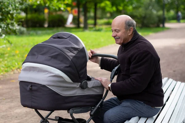 Dziadek pchający noworodka w wózku w parku — Zdjęcie stockowe