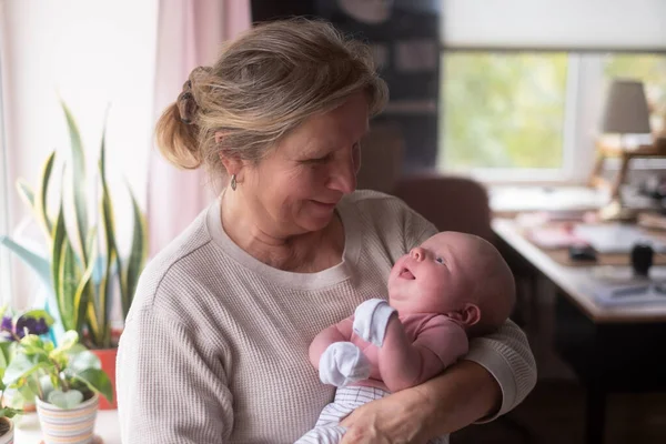 Elderly woman grandmother holding a newborn in her arms — Stock Photo, Image