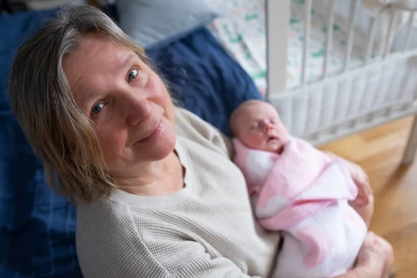 Elderly woman grandmother holding a newborn in her arms — Stock Photo, Image