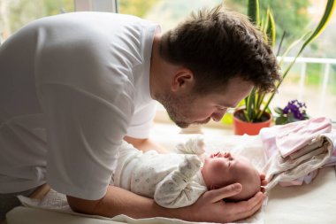 Genç beyaz bir baba yeni doğmuş kızına sarılıyor.