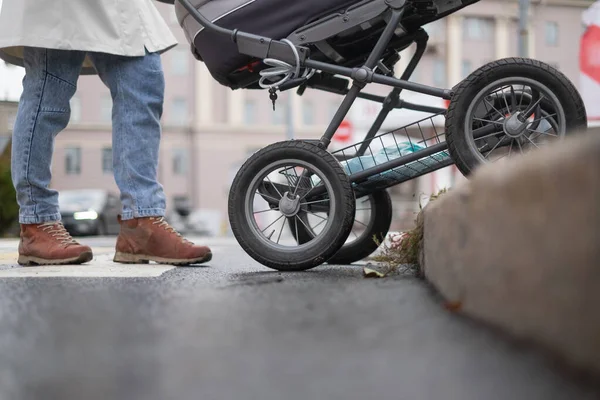 Moeder duwen baby kinderwagen bij een voetgangers kruising — Stockfoto