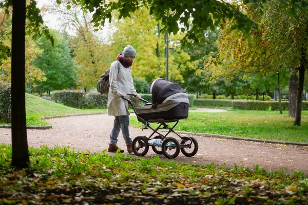 Happy young mother with pram during the walk — Stock Photo, Image