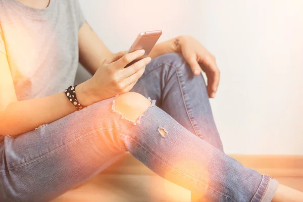 Closeup image of a teenager is searching information in network on mobile phone during free time. Young female student is revising photos on her cell telephone during break between lectures