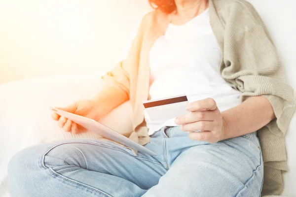 Internet shopping asian mature woman online with tablet pc and credit card. Internet shopper buying things on the internet showing blank tablet pc computer as sign.