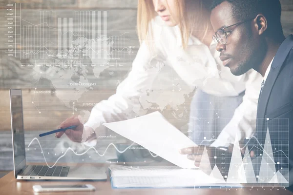 Double exposure. Visual effects. Two colleagues working together on business project using laptop: Caucasian woman holding a pen, pointing at diagrams and graphics on futuristic screen interface