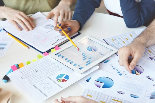 Cropped shot of people of diverse races working on business plan, analyzing value of goods, services, growth rate, making review of market situation, counting loss, using modern devices and touch pad