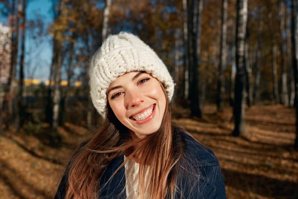 Portrait of a beautiful very cute autumn girl a knitted cap in city park. Fall woman portrait of happy lovely and beautiful caucasian young woman in forest in fall colors.