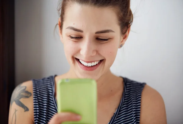 Portrait young funny woman happy, something on cell phone while texting receiving good sms text message isolated grey wall background. Human face expression emotion reaction.