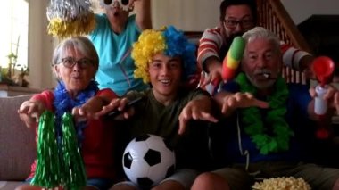 Komik kostümlü havalı bir aile futbol maçı izliyor ve takımı destekliyor.