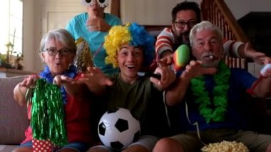 Komik kostümlü havalı bir aile futbol maçı izliyor ve takımı destekliyor.