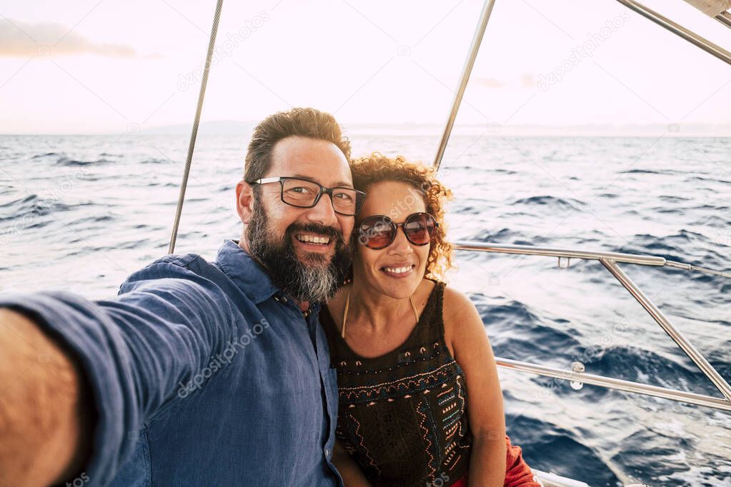 Cheerful people happy adult couple take selfie picture and enjoy together summer holiday vacation sailing with boat with ocean and sky in background 