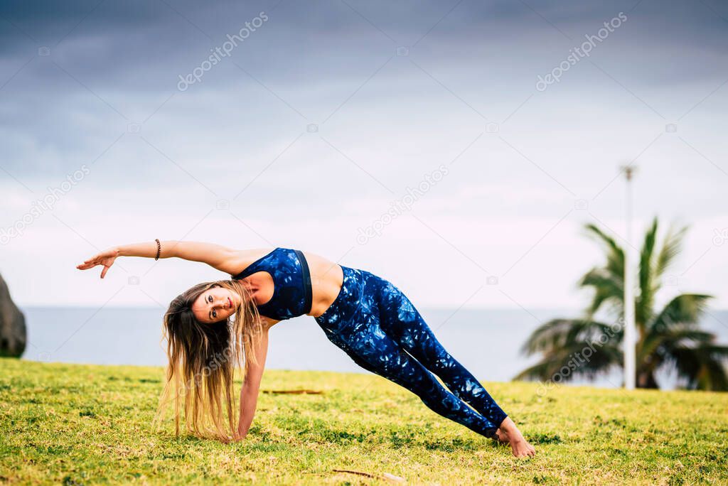 Beautiful young adult woman in balanced Pilates exercise position outdoor