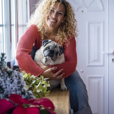 Neşeli köpek sahibi güzel yetişkin kadın evde köpeğine sevgiyle sarılıyor.