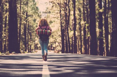 Seyahat eden insanlar, arka planda asfalt yol ve orman ormanlarının ortasında tek başına yürüyen bir kadınla birlikte alternatif sırt çantası özgürlük kavramına sahipler. 