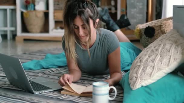 Молодая Женщина Читает Книгу Лежа Дома Ковре Рядом Ноутбуком Стеклом — стоковое видео