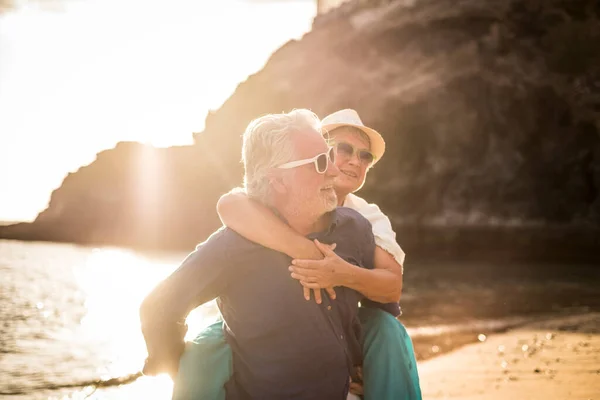 연애하는 나이든 부부는 해변에서 피기백으로 남녀와 시간을 즐긴다 — 스톡 사진