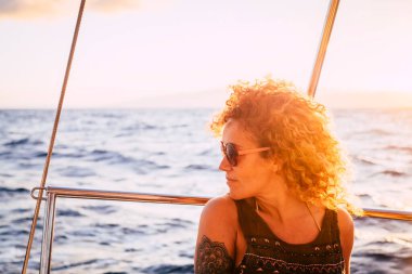 Güzel kadın gün batımının tadını çıkar. Deniz gezisi gezisinde yatta otur. 