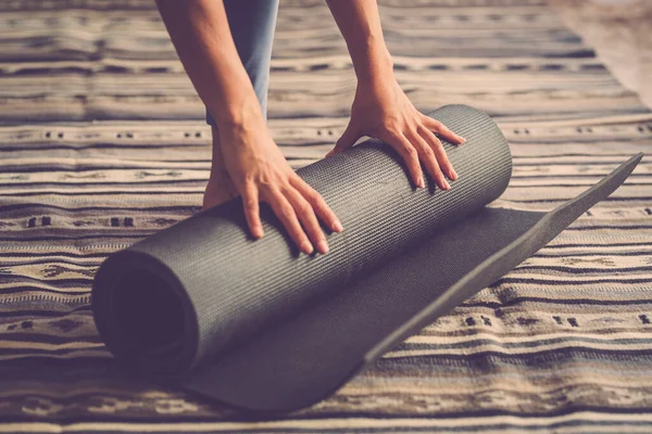 在每天积极锻炼的健身室内锻炼结束后 女性双手从地板上摘下瑜伽垫的近距离接触 — 图库照片