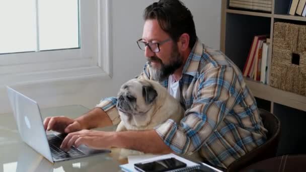 有胡子的成年人在家里和他的朋友狗一起在办公室里工作 他们的生活方式也很现代 有网络连接和笔记本电脑 — 图库视频影像
