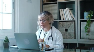 Kadın doktor evde dizüstü bilgisayarla çalışıyor, koronavirüs konsepti.