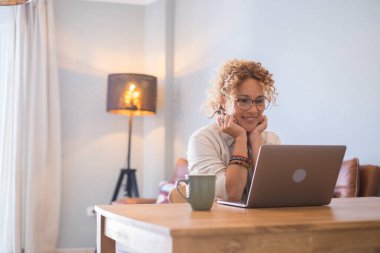 Evde bilgisayar başında çalışan mutlu bir genç kadın fotoğrafçı.