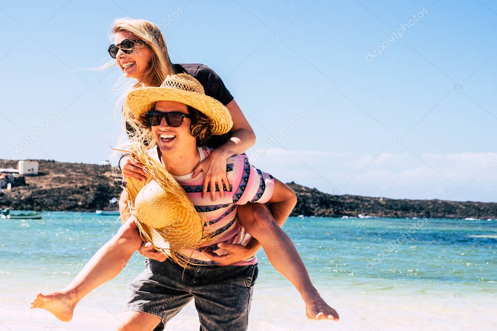 summer holiday vacation people with beach and blue sea water in background - youthful couple have fun together outdoor