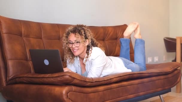快乐漂亮的成年女子躺在沙发上 在网上做视频通话 — 图库视频影像