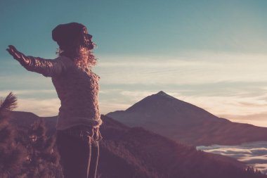 Happy free woman open arms and enjoy the amazing beautiful sunset at the mountain