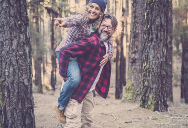 Neşeli, mutlu, yakışıklı beyaz çift ormanda yürürken sırtlarını sıvazlıyorlar.