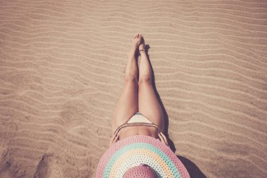 Yaz zamanı kadınlar bronz tenleri için güneş banyosu yaparlar - hasır şapkalı çekici kadın bikini mayosuyla kumsalda uzanır - eski tarz moda renkler - seyahat tatili